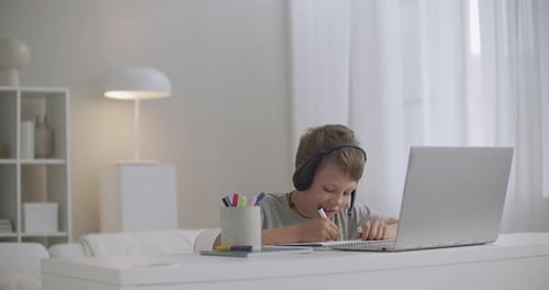 Young Boy Doing Schoolwork at Desk with Laptop