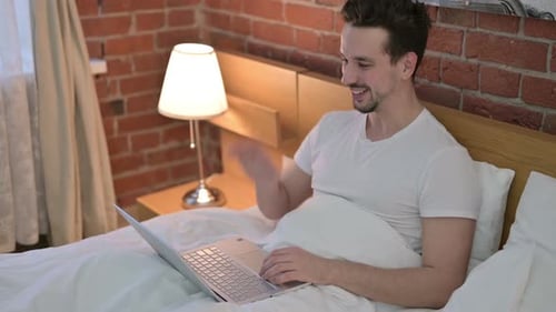 Man Video Calling on Laptop in Bed