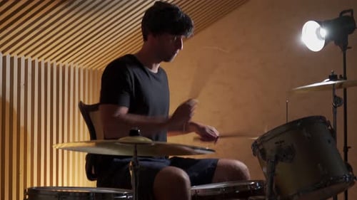 Young Man Plays Drums in Recording Studio
