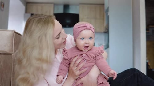 Mother and Baby Girl with Blue Eyes and Blond Hair Sitting in Front of the Camera