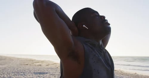 Man Stretching Arms on Beach After Exercise