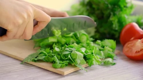 Chopping fresh green parsley on cutting board