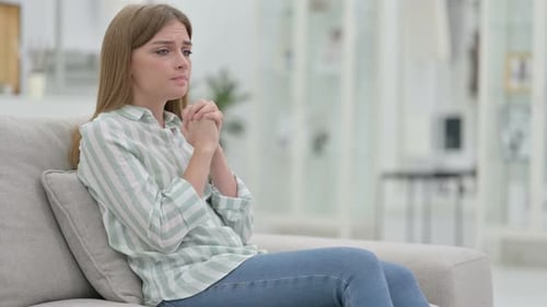 Woman Sitting on Couch Looking Distraught