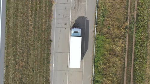Aerial View of Truck with White Cargo Trailer Driving on Empty Road and Transporting Goods. Flying