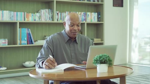 Man Using Laptop and Writing at Home