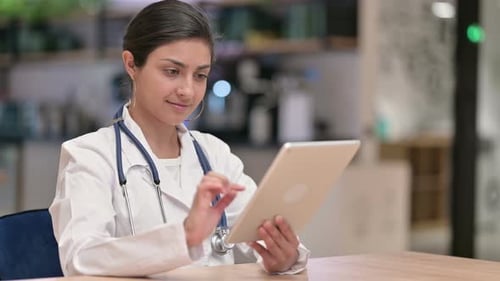 Serious Professional Indian Female Doctor Using Tablet in Cafe