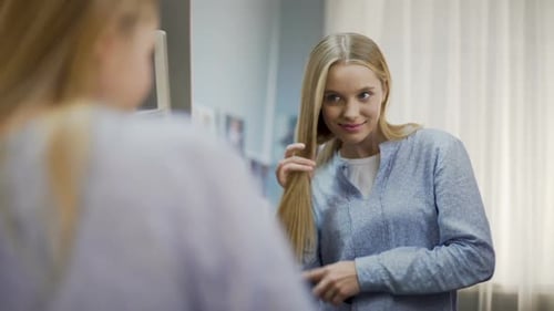 Blonde Woman Brushing Hair in Bedroom Mirror
