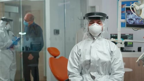 Dentist in Coverall Looking and Smiling at Camera