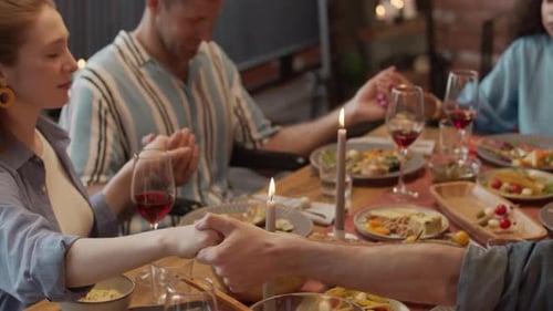 Group of Friends Praying at Dinner Table