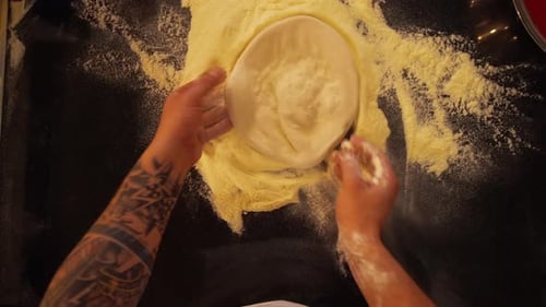 Overhead View of Professional Cook Rolling Pizza Dough Into a Flat Pizza Bread