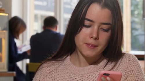Attractive Woman Drinking Coffee, Using Her Smart Phone at the Cafe