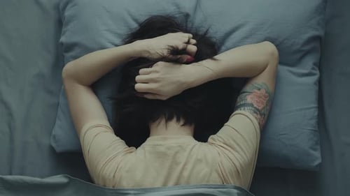 Woman Lying in Bed with Hands Behind Head
