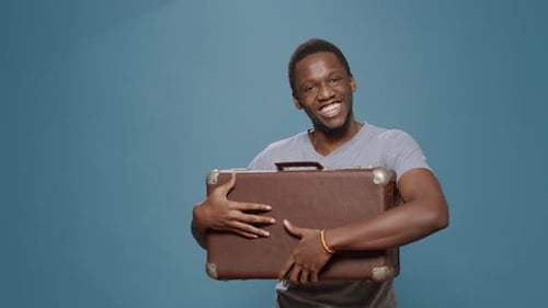 Young Man Smiling and Holding Brown Suitcase
