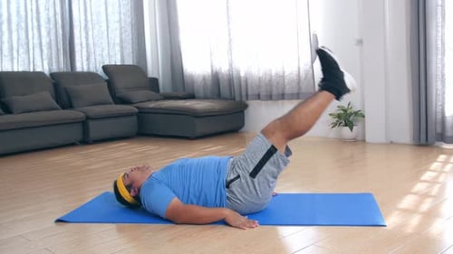 Man Doing Leg Raises on Exercise Mat Indoors