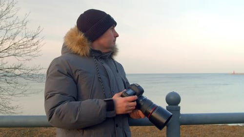 Man with Camera by Ocean during Golden Hour