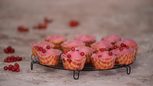 Currant Muffins with Pink Icing Being Decorated
