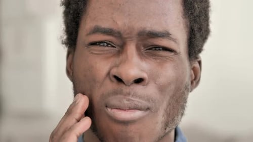 Zahnschmerzen, Nahaufnahme eines afrikanischen Mannes mit Zahnschmerzen