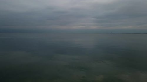 Slowmotion aerial shot of Seagull flies above calm sea at cloudy autumn day