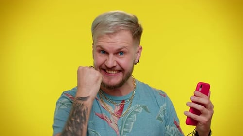 Excited Man Celebrates with Mobile Phone Success