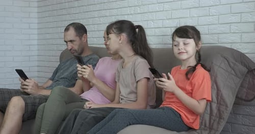 Family Relaxing Together with Phones on Couch