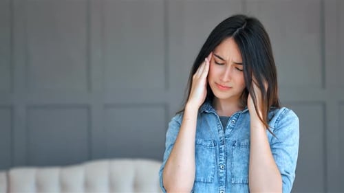 Young Woman Massaging Temples Indoors