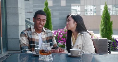 Smiling couple drinks tea at outdoor cafe