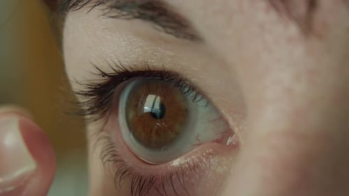 Femme aux yeux bruns mettant une lentille de contact souple sur son œil, gros plan