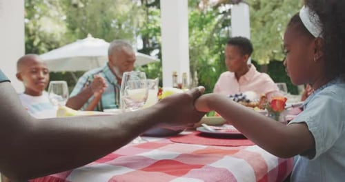 Family Holds Hands Praying Before Meal Outdoors