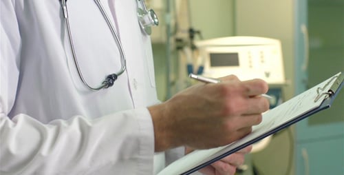 Doctor Writing on Clipboard in Hospital Setting