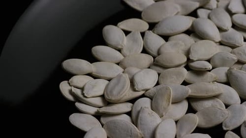 Close-Up of White Pumpkin Seeds on Dark Surface