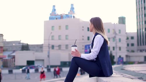 Jolie fille le soir dans le centre-ville, dans un costume d'affaires, buvant un café et tenant