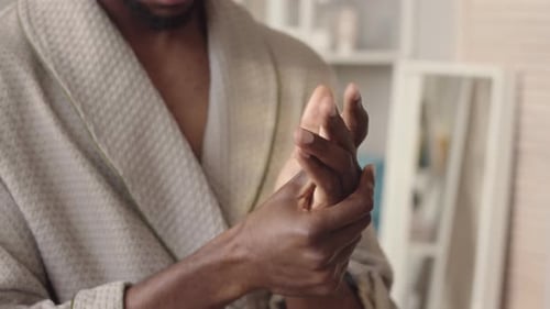 Man Applying Lotion to Hands in Bathroom