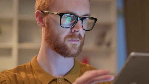 Nahaufnahme eines seriösen rothaarigen Mannes mit digitalem Tablet