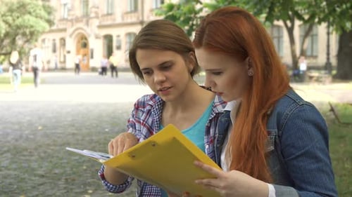 Studentinnen schauen sich ein Journal auf dem Campus an