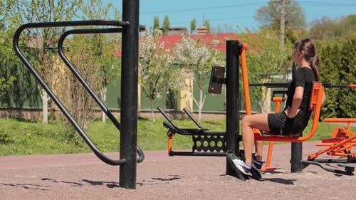 Woman Exercising on Leg Machine in Outdoor Gym