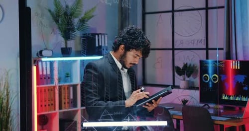Homme d'affaires en costume vérifiant les informations sur une tablette PC et les comparant avec les données sur un panneau en verre