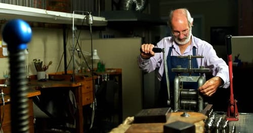 Goldsmith working on machine in workshop
