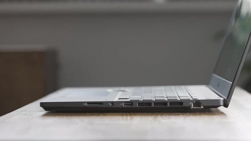 Laptop Closed by Hand on Wooden Desk