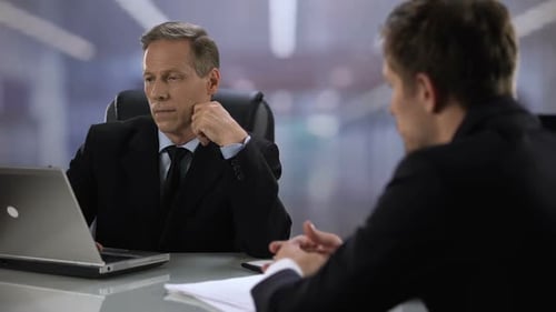 Un locataire inattentif regarde un ordinateur portable lors d'un entretien d'embauche avec un candidat
