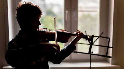 Young Person Playing Violin by Window Indoors
