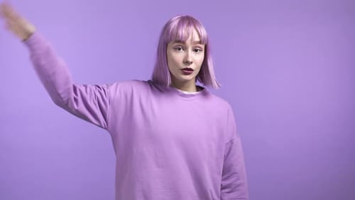 Stylish Woman Waving Hello Against Purple Background
