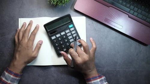 Nahaufnahme eines Buchhalters mit Taschenrechner auf Office Desk