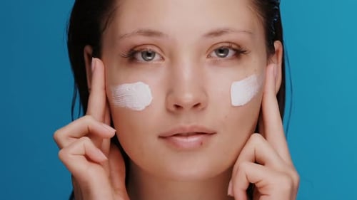 Woman Applying White Cream to Face Smiling