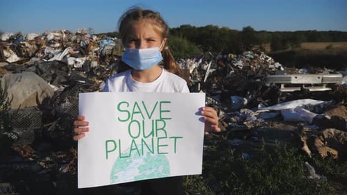 Young Child Holds "Save Our Planet" Sign at Dump