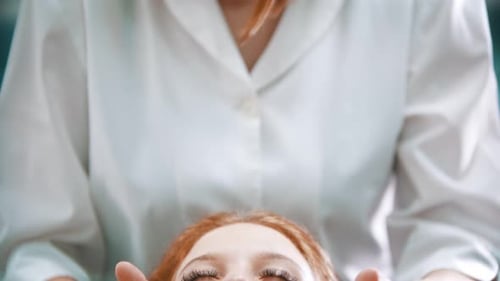 Massage - Schöner Massagemeister, der das Gesicht einer Frau massiert