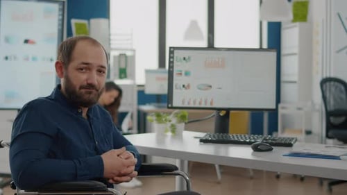 Man in Wheelchair Smiling in Modern Office