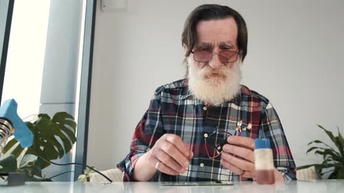 Senior Engineer Repairs Electronic Components at Desk