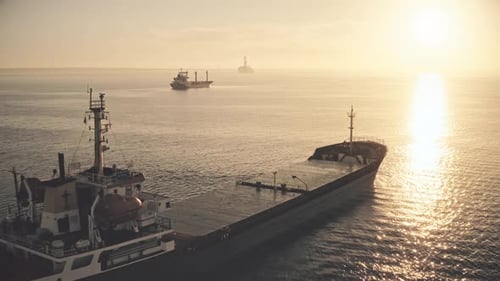 Cargo Ship Sailing at Sunrise in the Open Ocean