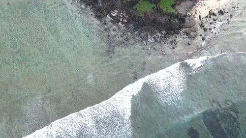 Aerial View of Waves Meeting a Rocky Beach