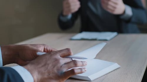 Gros plan Des mains d'un homme écrit une note dans un carnet en gros plan Un couple de collègues multiethniques assis